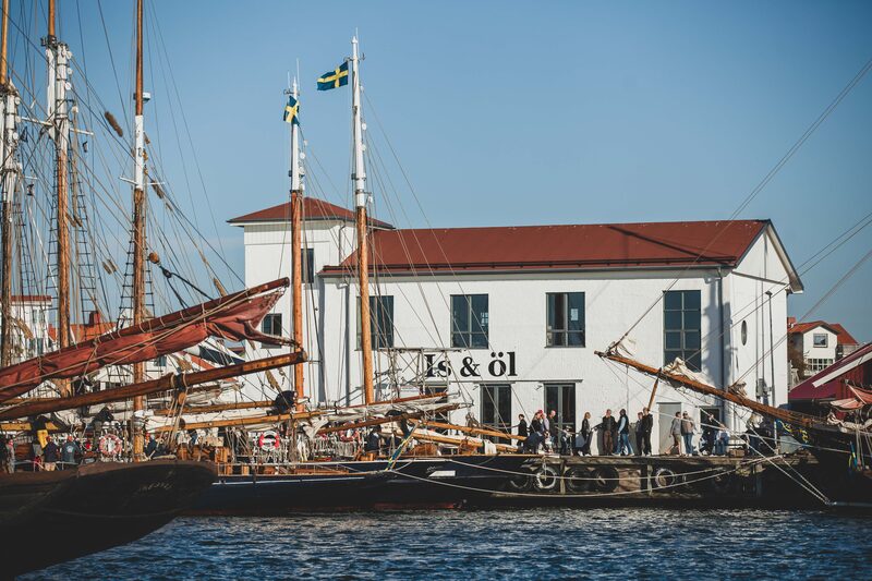 Högmastade segelfartyg bredvid ett vitt hus i hamnen